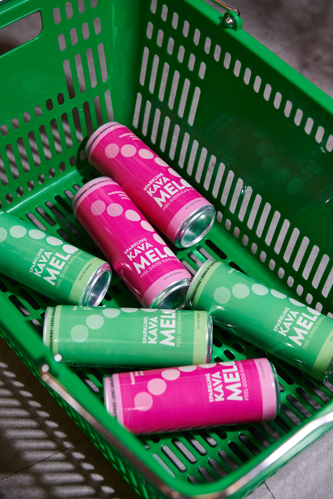 Green and pink Kava Melo cans in a green shopping basket.