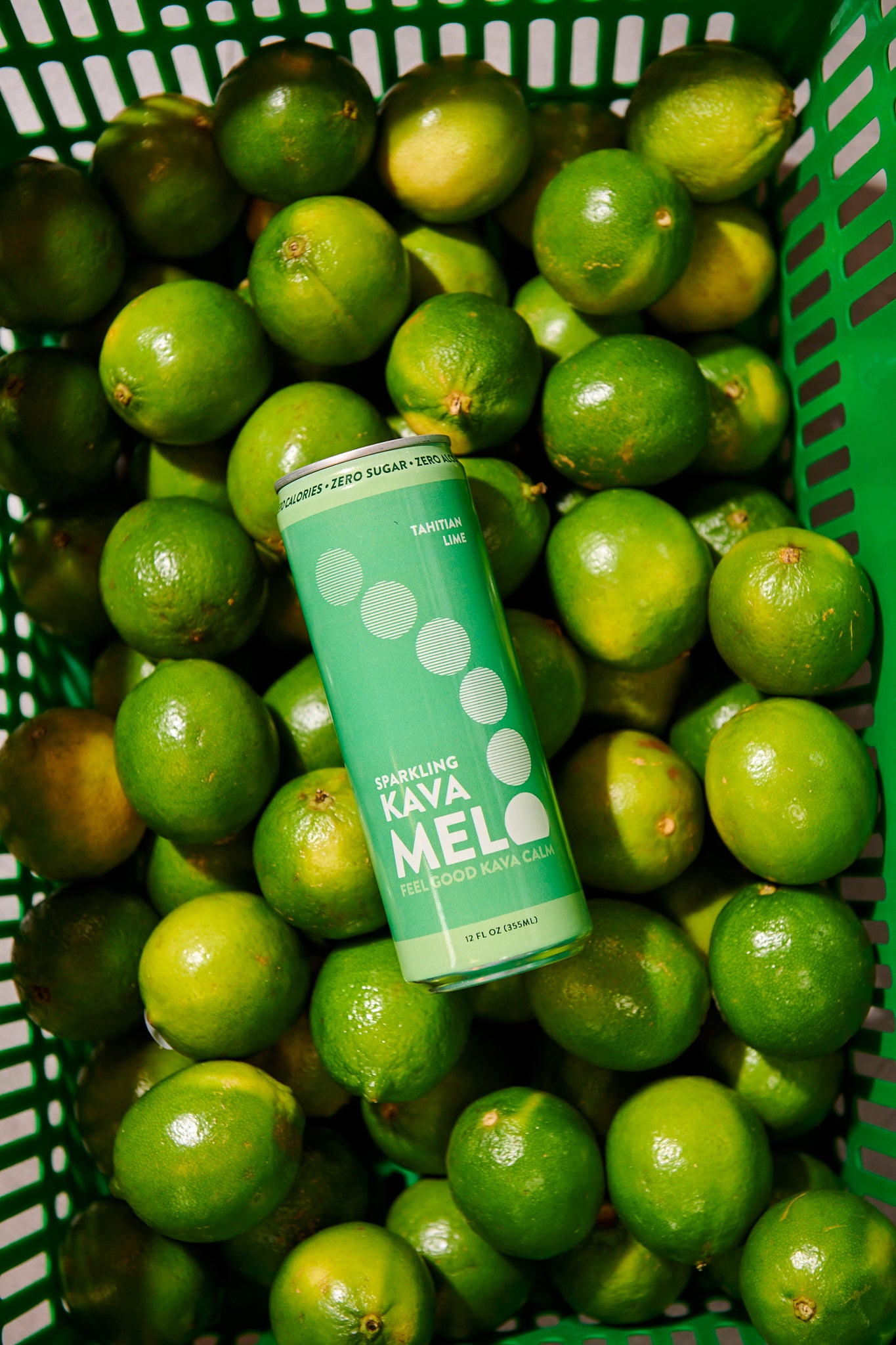 Green can of Kava Mela surrounded by green limes in a basket