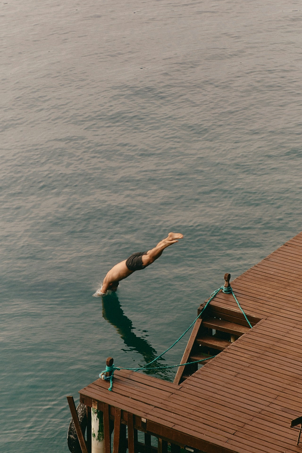 Person diving into water from a wooden dock