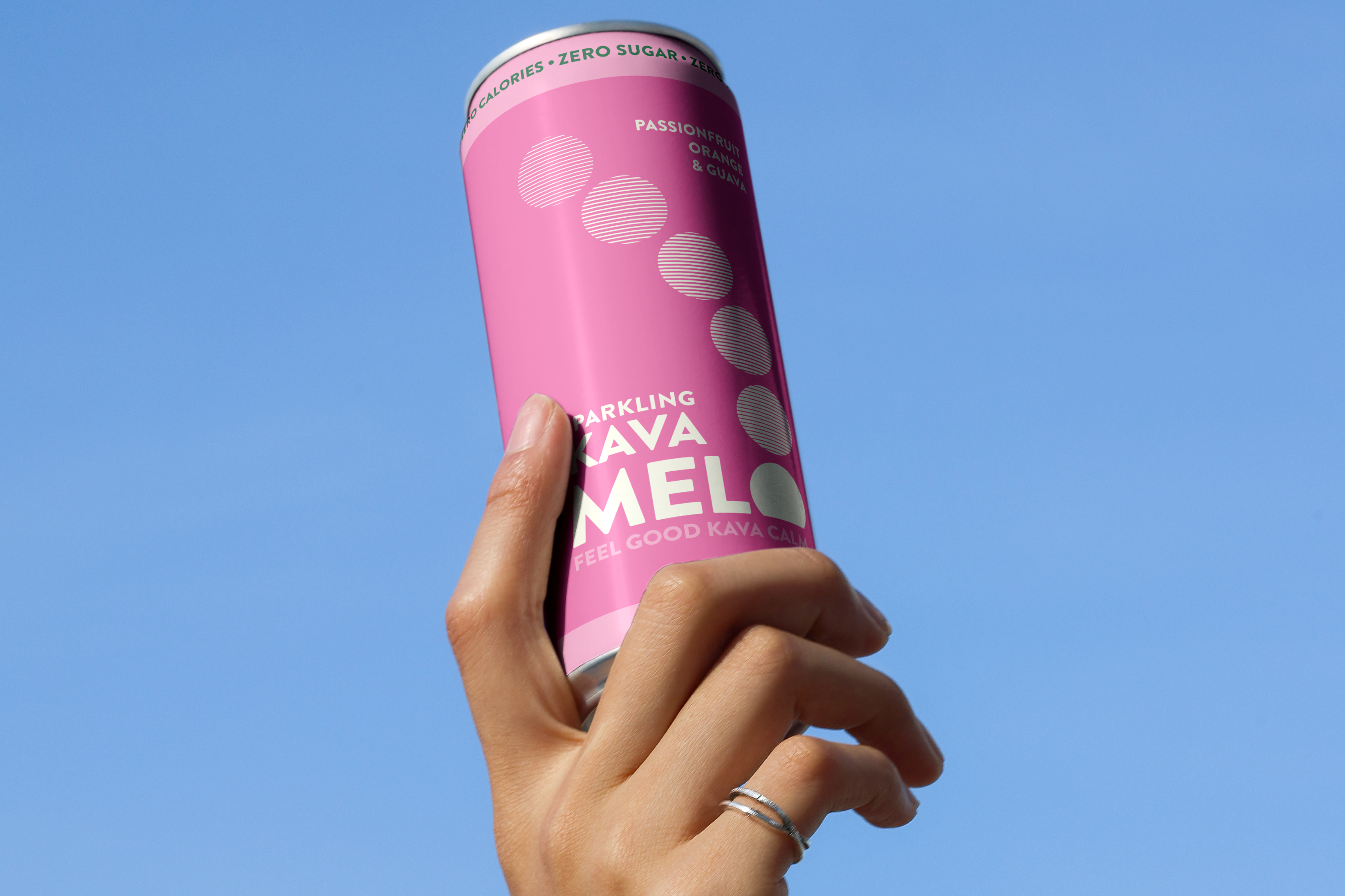 Hand holding a pink can against a clear blue sky