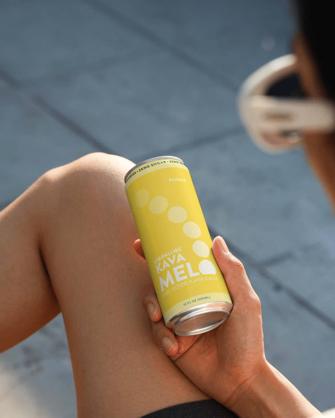 Hand holding a yellow can with 'Kava Mel' branding on a blurred background
