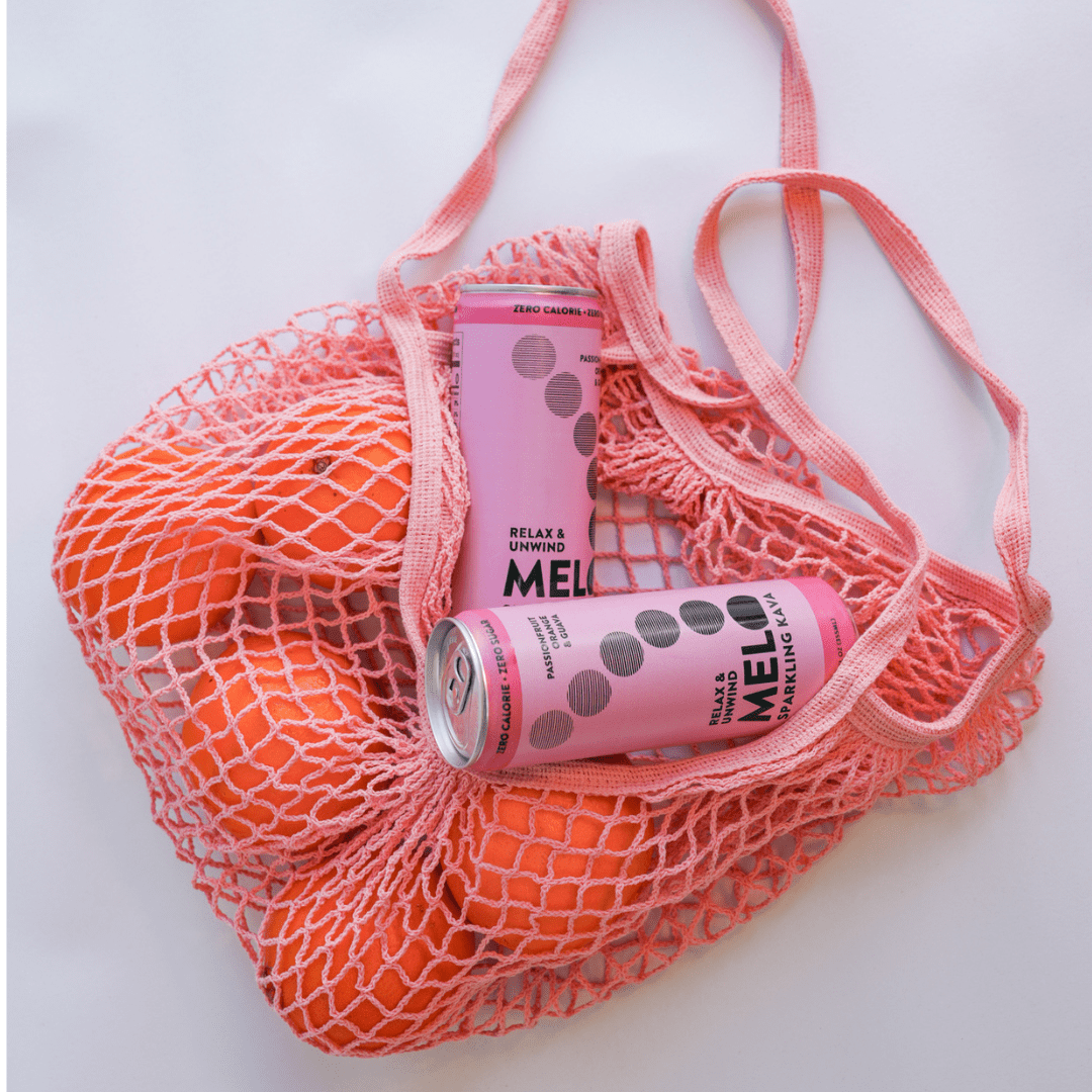 Pink cans with 'Melo' branding in an orange mesh bag on a white background