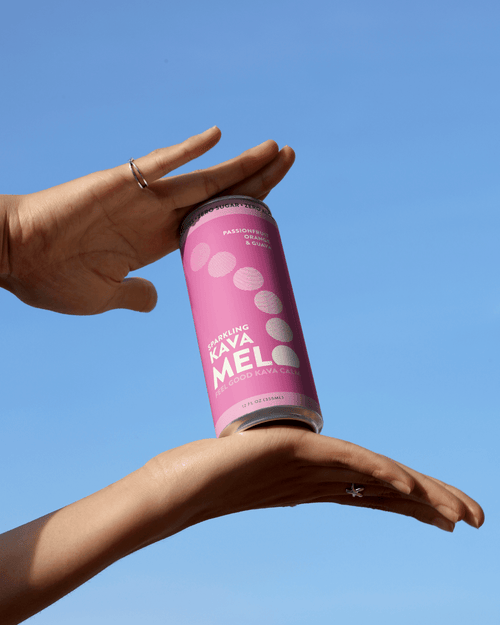 Person holding a pink can against a clear blue sky