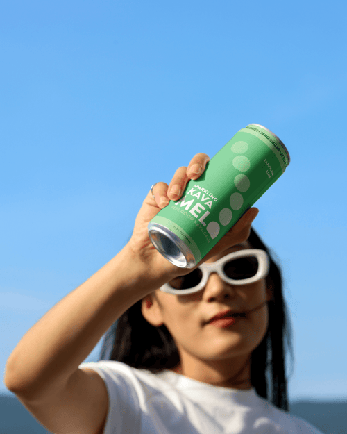 Person holding a green can against a clear blue sky